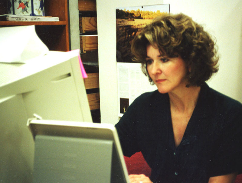 photograph of smiling woman holding an artifact and brush