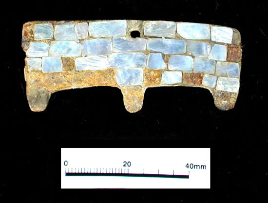 Opalescent mother-of-pearl from Pacific coast abalone shells has been cut into squares to form a mosaic pattern in this ornament. Although the shell appears inset, they are glued in, likely with a substance derived from pitch.