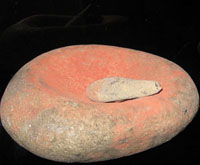 photo of a concave stone (metate) with a smaller hand stone (mano)