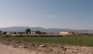 photo of scattered houses of Mexican community on ridge above green fields