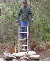 photo of Aaron Norment standing above the intact rock chimney foundation