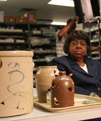 photo of Winnie (Harper) Moyer examining reconstructed stoneware vessels from the Williams farmstead.