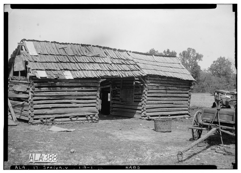 Black and white photo of old dog-run log barn with a wood shingle roof