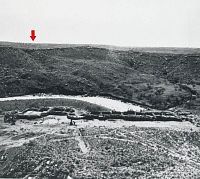 Old photo showing canyon with linear arrangement of low stone walls in foreground.