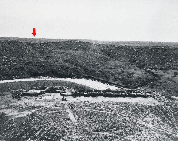 Old photo showing canyon setting with rubble mounds and tire tracks in foreground.