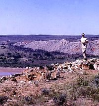 Color photo of man standing on low ruins.