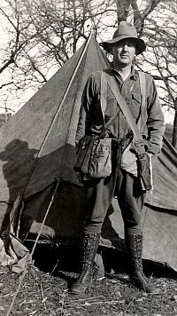 Photo of man standing in front of canvas tent.